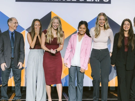 Dean Papajohn, Lily Trenkamp, Lauren Johnson, Reuel Florendo, Kenadee Carruthers and Macie Balkan celebrate a win on an expo stage