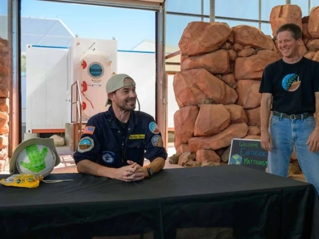 Matthias Beach sitting at a table and Kai Staats standing nearby, both smiling