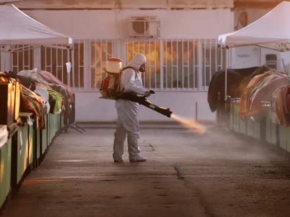 A worker in protective clothing disinfects surfaces in a market where meat is sold. 